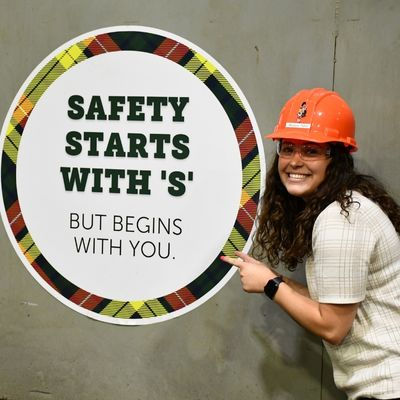 Woman pointing at a sign, "Safety Starts With 'S'" with safety message.