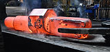 Hot eccentric shaft forging, alos called a spindle forging, being handled by a manipulator