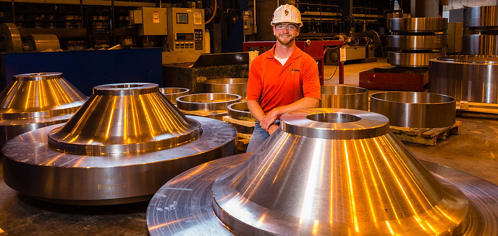 Man in hard hat sits near metal parts in a factory Scot Forge
