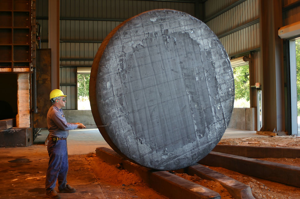 Worker measuring a massive steel disc, inside a Scot Forge industrial facility.