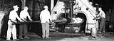Historic photo of workers operating large machinery at Scot Forge, with metal being forged.