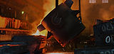 Molten metal being poured in a factory, heavy machinery in action to produce an ingot.